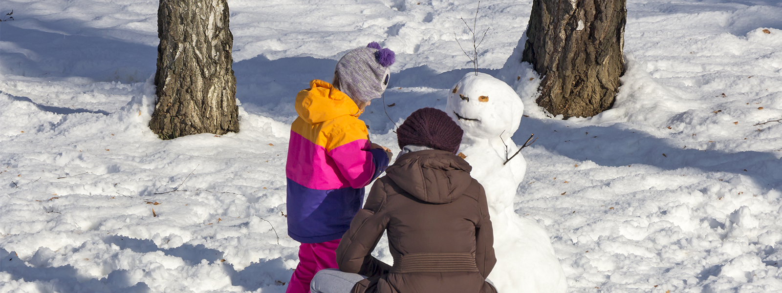 lapsi ja aikuinen rakentavat lumiukkoa